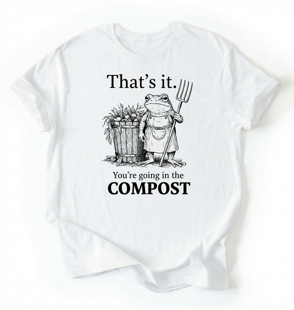 Flat lay of a White t-shirt featuring an illustrated frog with text reading “That’s it you’re going in the compost frog t-shirt” on a white background