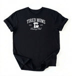 Flat lay of a black Tired Moms Baking Club graphic shirt with stand mixer design for baking moms on a white background 