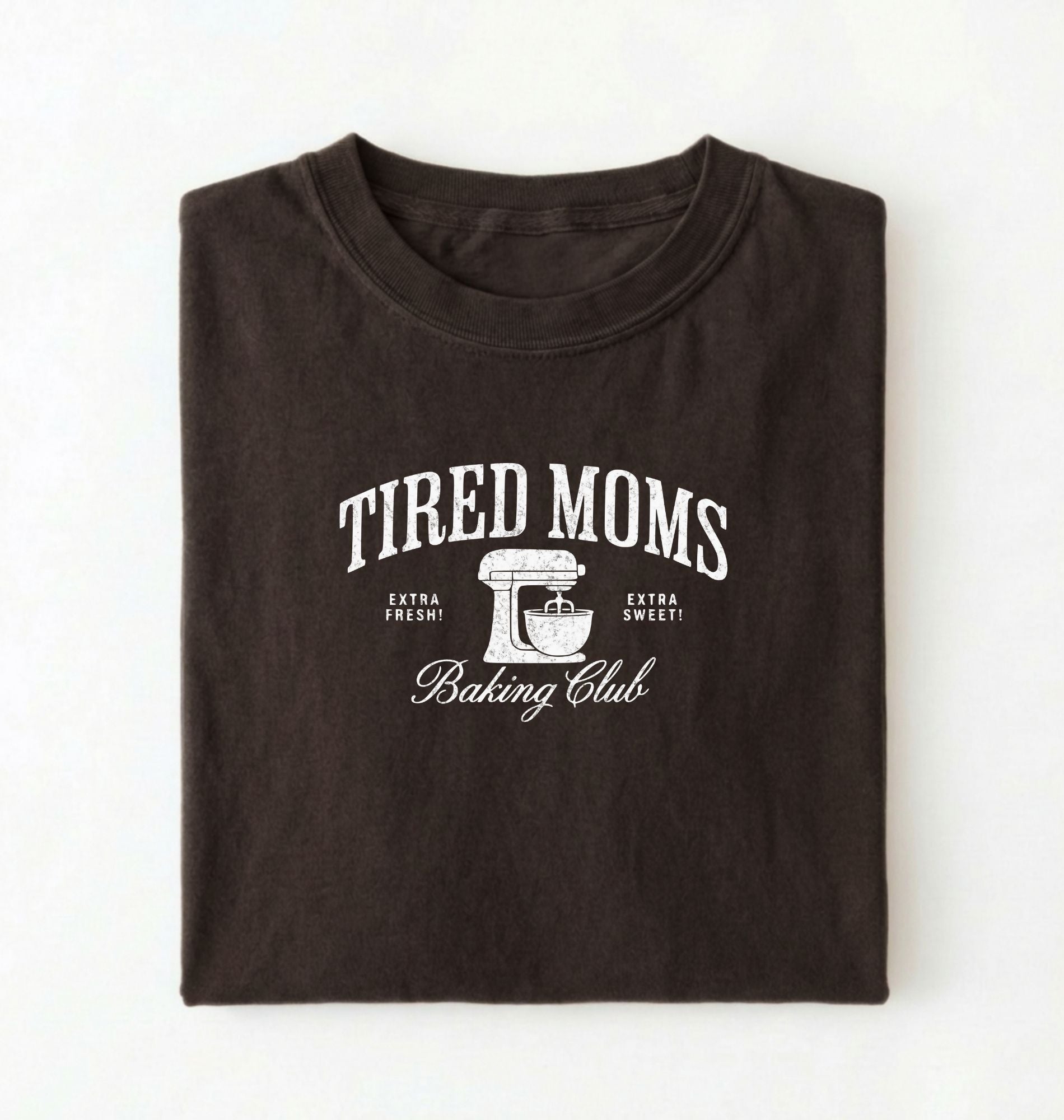 Flat lay of a brown Tired Moms Baking Club graphic shirt with stand mixer design for baking moms on a white background 