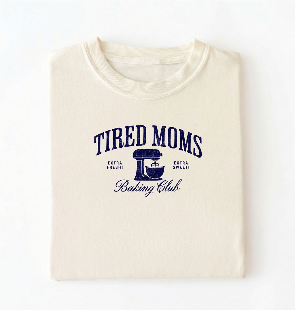 Flat lay of a ivory Tired Moms Baking Club graphic shirt with stand mixer design for baking moms on a white background 