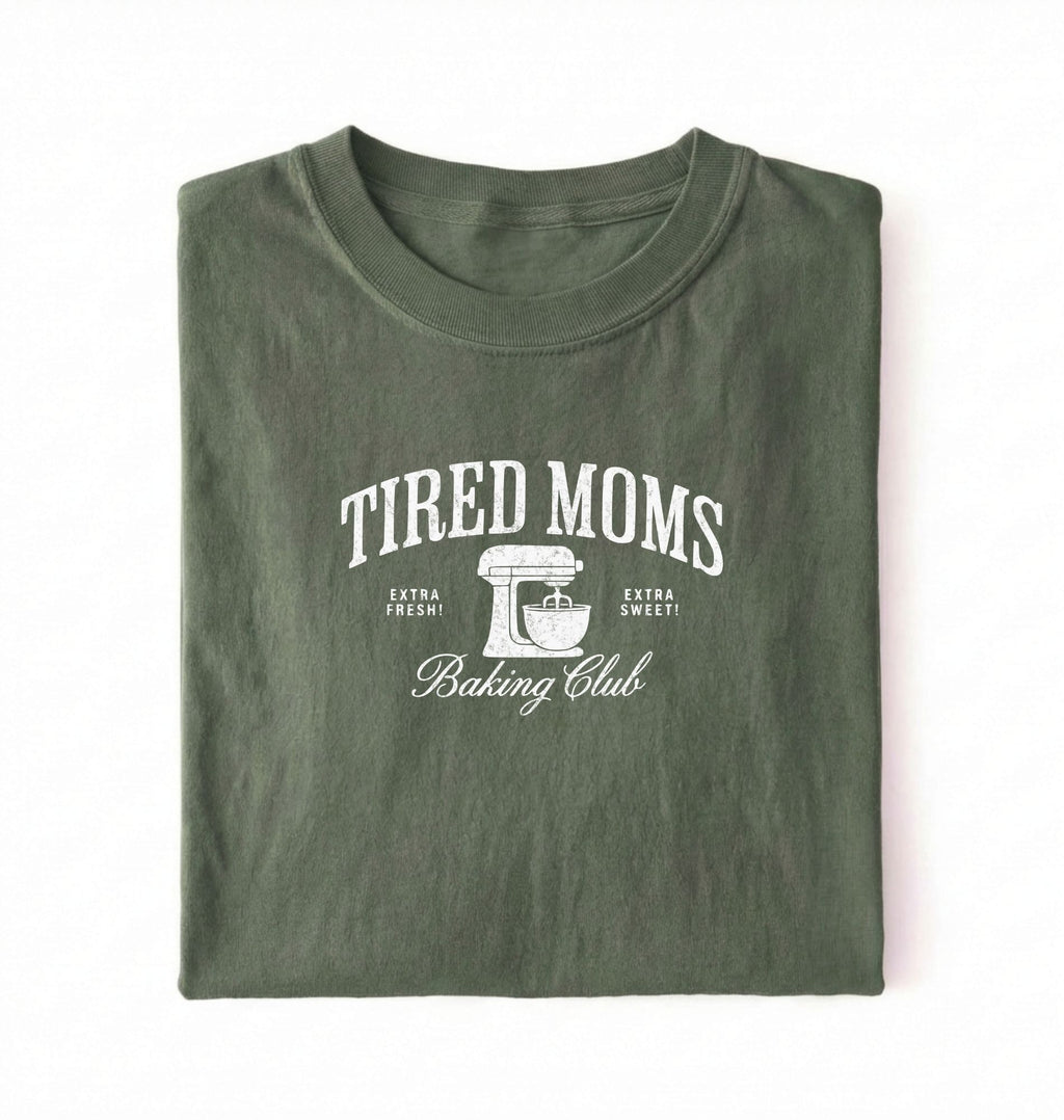 Flat lay of a green Tired Moms Baking Club graphic shirt with stand mixer design for baking moms on a white background 