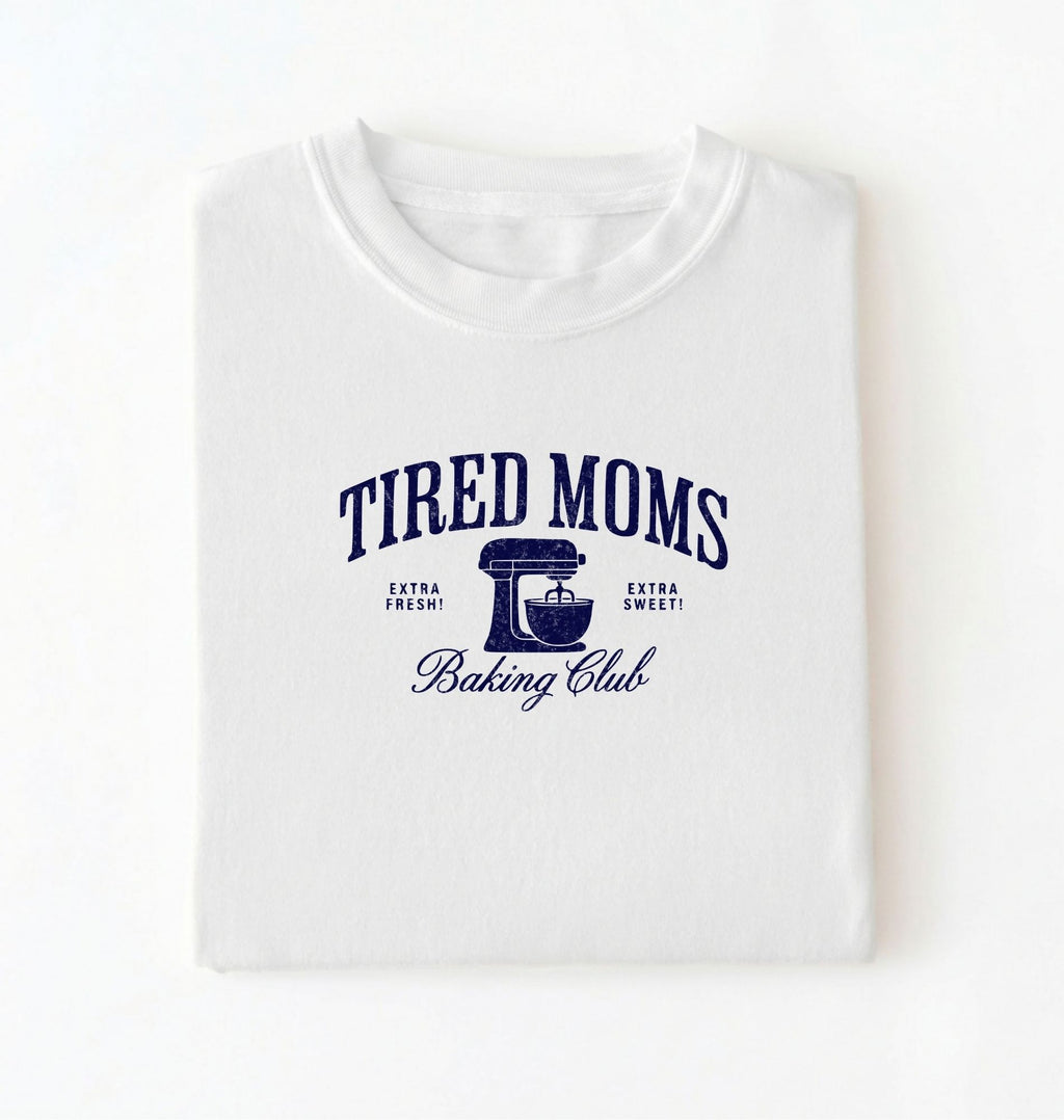 Flat lay of a white Tired Moms Baking Club graphic shirt with stand mixer design for baking moms on a white background 