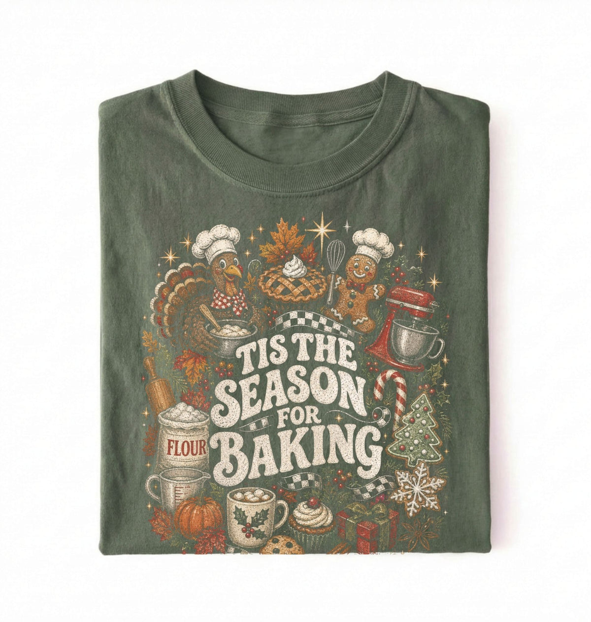 A folded dark olive green t-shirt with a colorful 'Tis the Season for Baking' graphic print featuring illustrations of a turkey, gingerbread man, stand mixer, flour sack, and cupcakes on a white background.