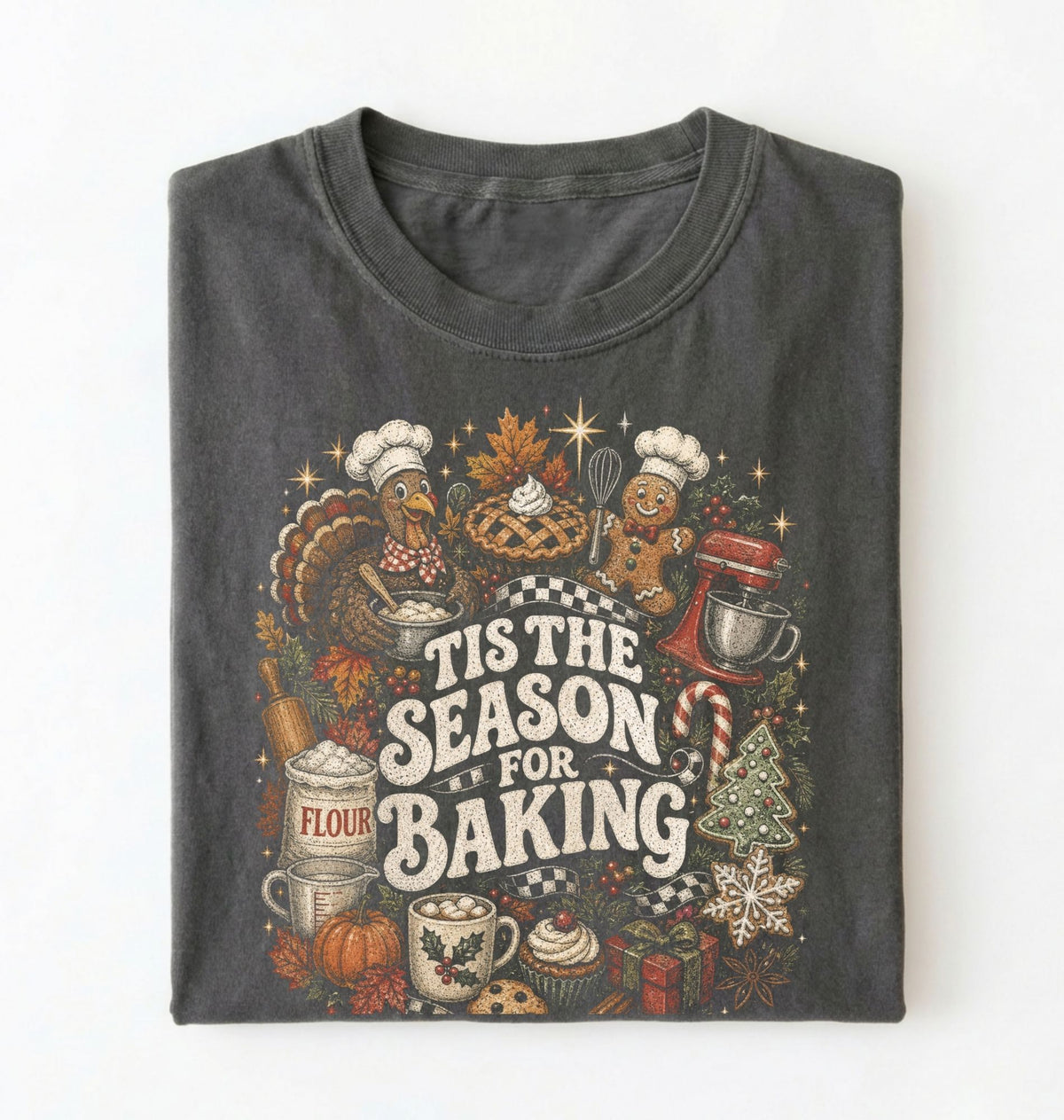 A folded dark gray t-shirt with a detailed holiday baking graphic on the front, featuring illustrations of a turkey, gingerbread man, pie, flour sack, and the text 'TIS THE SEASON FOR BAKING' on a white background.