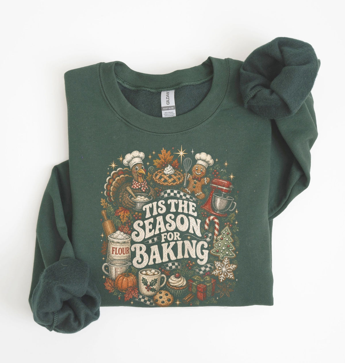 A dark forest green long-sleeve sweatshirt with a festive 'Tis the Season for Baking' graphic print, styled flat on a white background with one sleeve folded over.