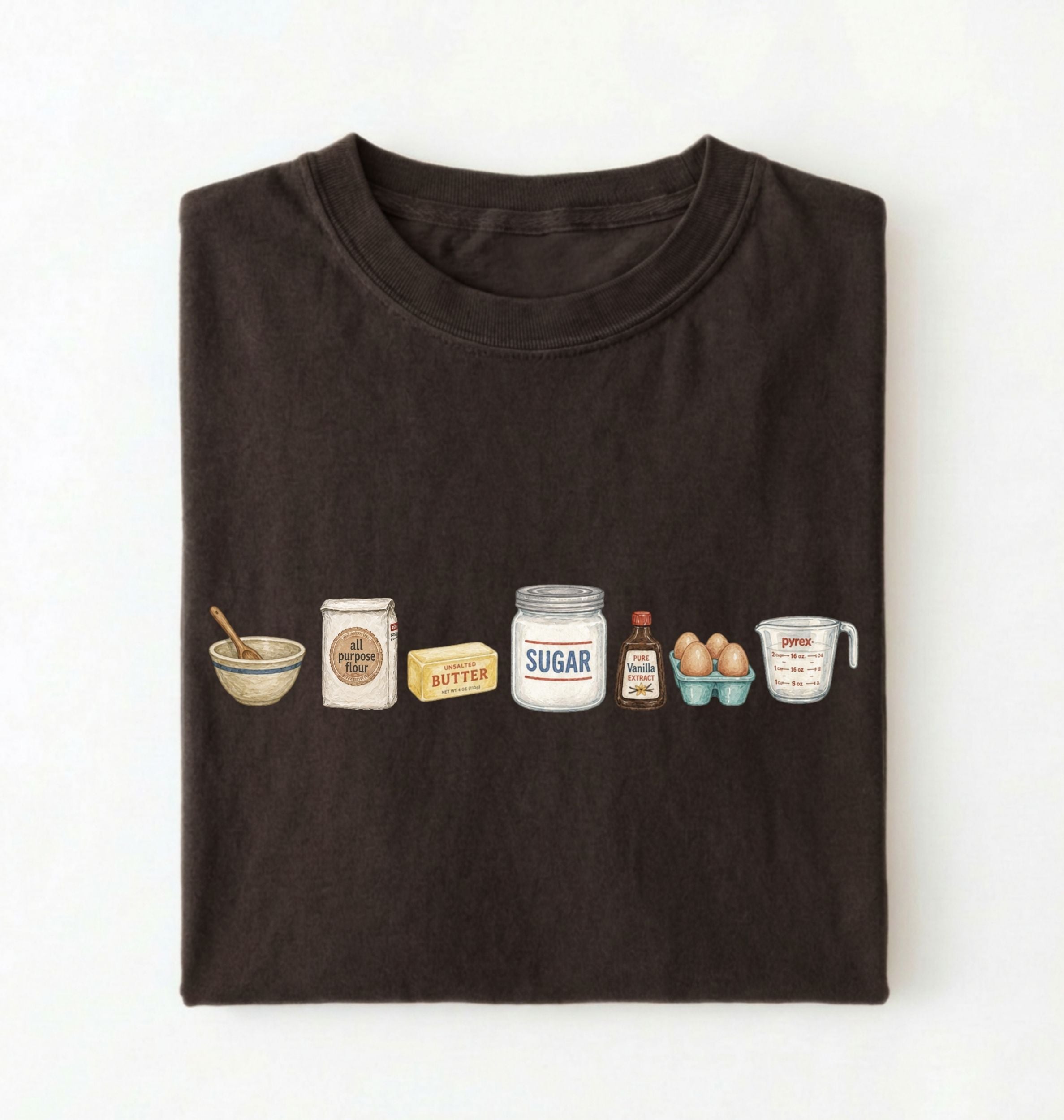 A dark brown folded t-shirt on a white background, featuring a graphic print of baking ingredients including a bowl, flour, butter, sugar, vanilla, and eggs.