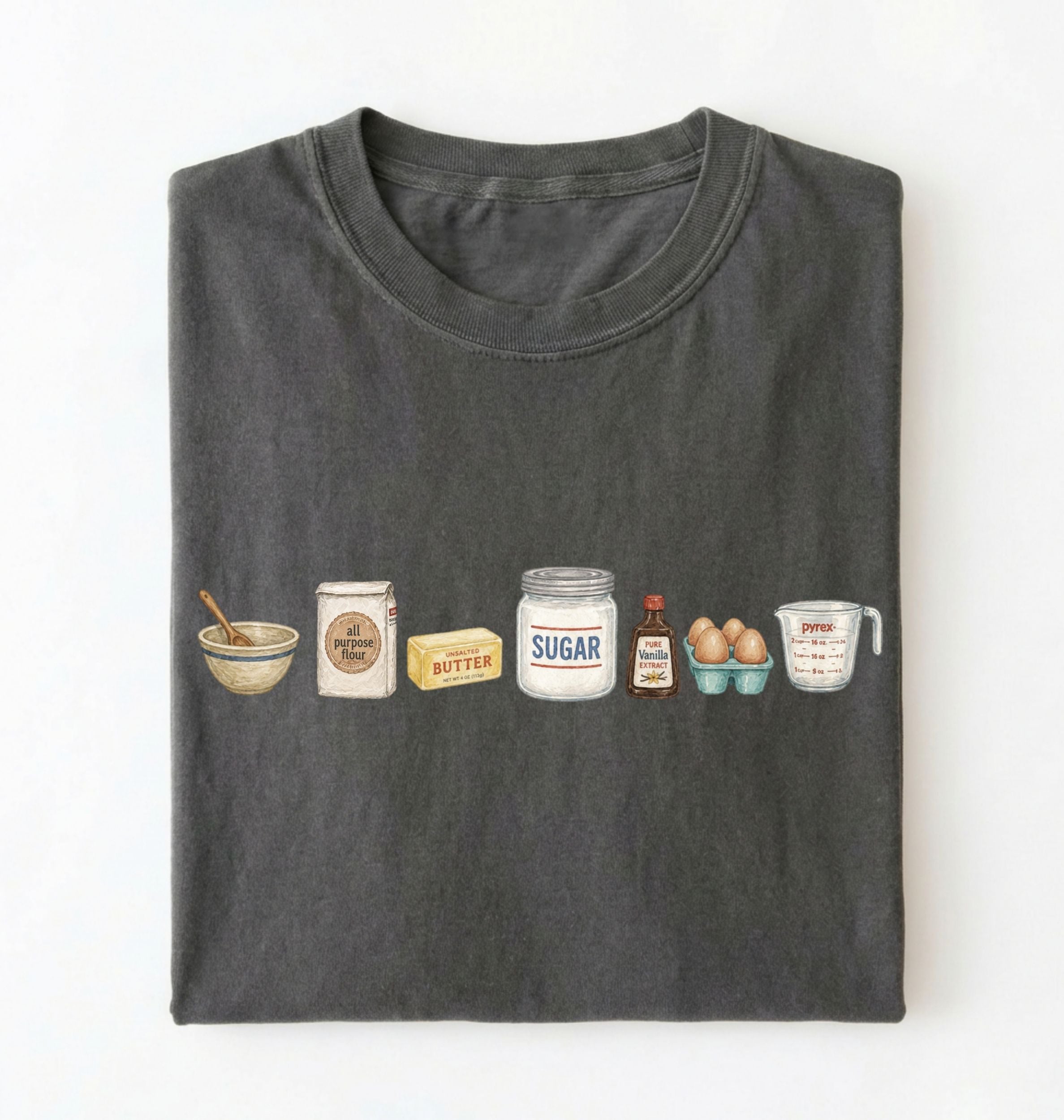 A dark gray folded t-shirt on a white background, featuring a graphic print of baking ingredients including a bowl, flour bag, butter, sugar jar, vanilla bottle, eggs, and a measuring cup.