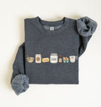 A dark heather gray crewneck sweatshirt with rolled-up sleeves, featuring a graphic print of baking ingredients (bowl, flour sack, butter, sugar jar, eggs, and measuring cup) across the chest, laid flat on a white background.