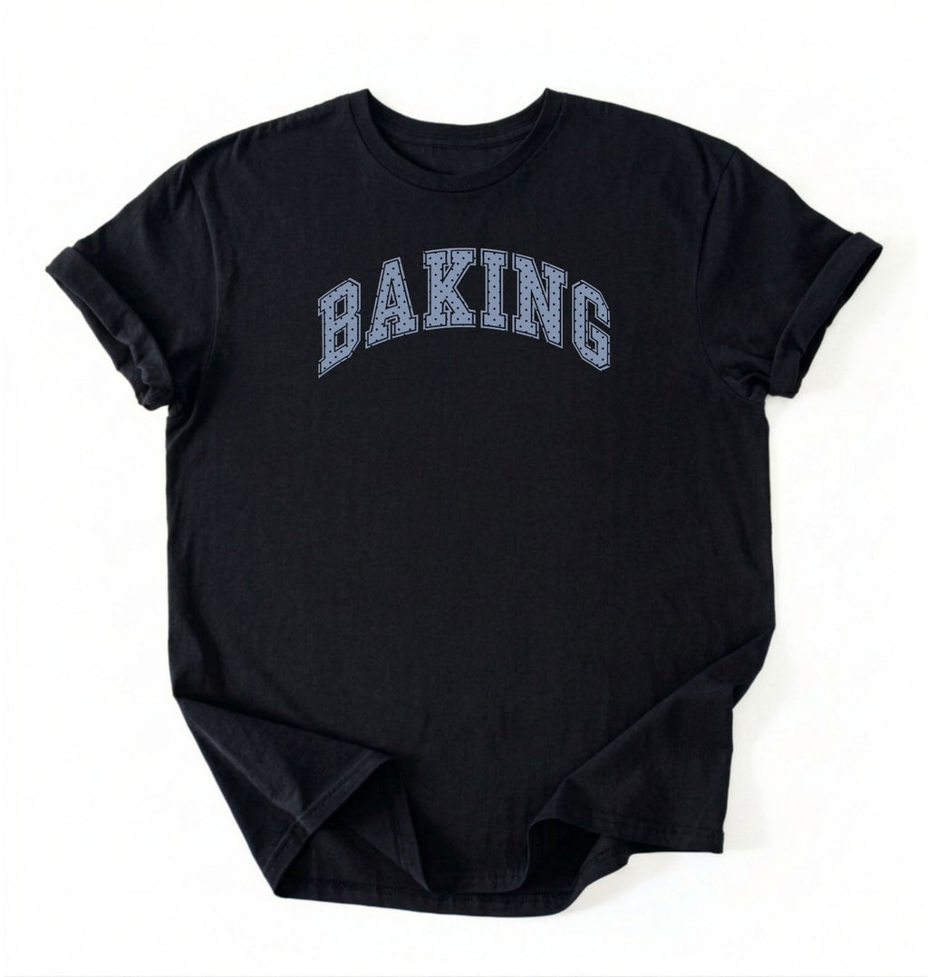 A black short-sleeve t-shirt with the word 'BAKING' printed in an arched, collegiate-style font across the chest. The letters are filled with a light blue and white textured pattern resembling a checkerboard or grid.