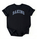 A black short-sleeve t-shirt with the word 'BAKING' printed in an arched, collegiate-style font across the chest. The letters are filled with a light blue and white textured pattern resembling a checkerboard or grid.