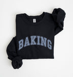 A black long-sleeve sweatshirt with 'BAKING' printed in arched varsity letters across the chest. The letters feature a light blue and white patterned fill.
