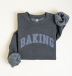 A folded dark heather gray sweatshirt with 'BAKING' printed across the chest in light blue varsity-style letters, shown on a plain off-white background.