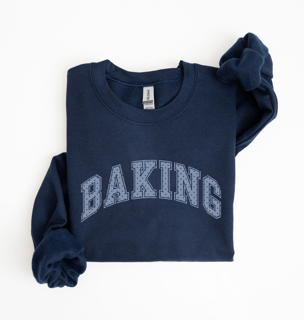 A navy blue sweatshirt with 'BAKING' printed in arched varsity letters across the chest, folded neatly on a white background.