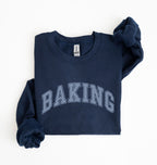 A navy blue sweatshirt with 'BAKING' printed in arched varsity letters across the chest, folded neatly on a white background.