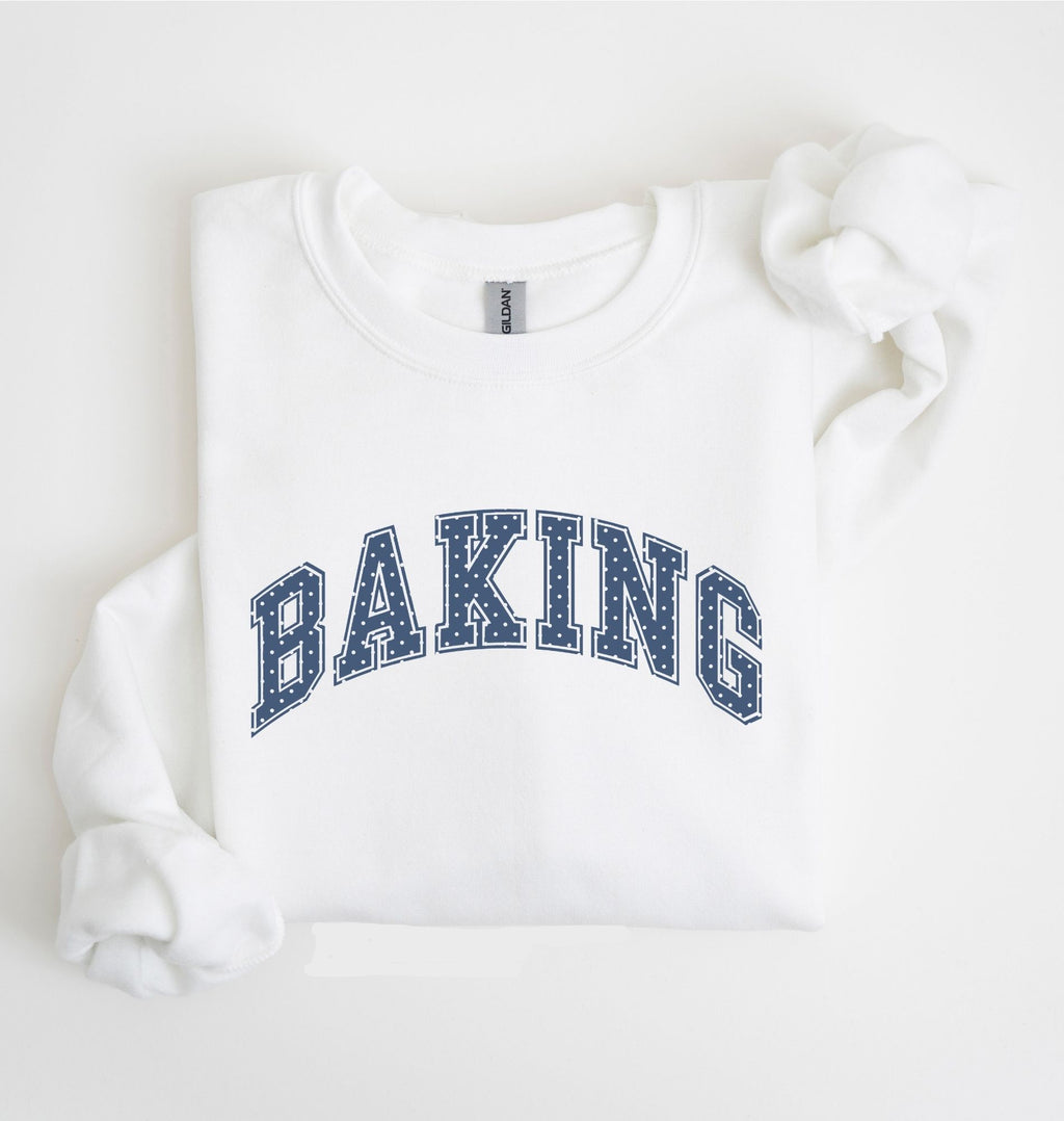 A white long-sleeve sweatshirt with 'BAKING' printed in navy blue varsity-style block letters across the chest, laid flat on a white background.