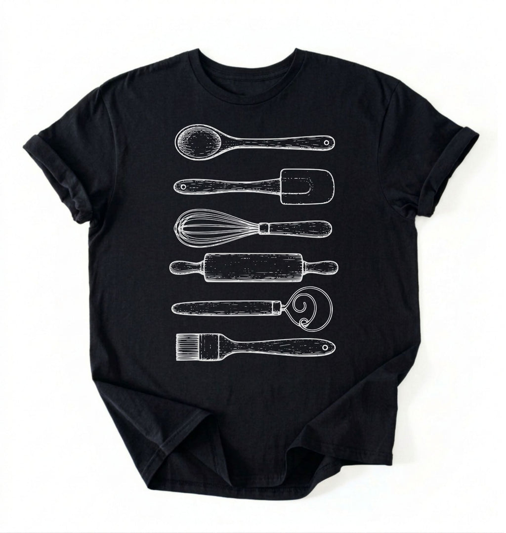 Flat ay of a Vintage baking tools shirt with whisk rolling pin and spatula illustrations on black tee on a white background 