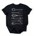 Flat ay of a Vintage baking tools shirt with whisk rolling pin and spatula illustrations on black tee on a white background 