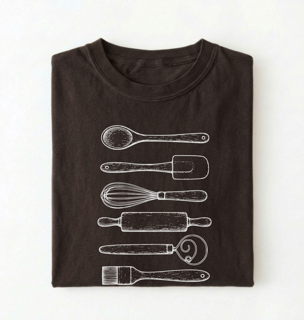 Flat ay of a Vintage baking tools shirt with whisk rolling pin and spatula illustrations on brown tee on a white background 