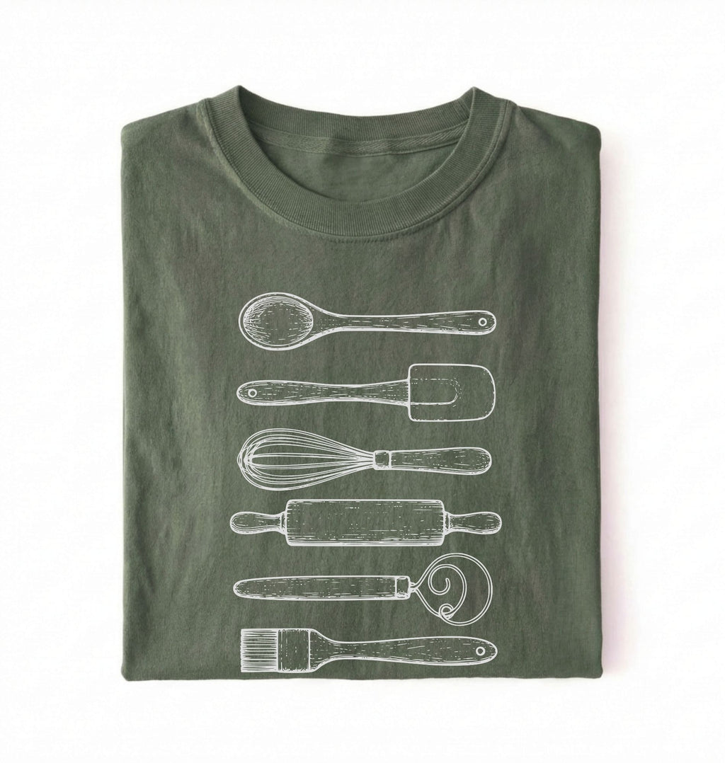 Flat ay of a Vintage baking tools shirt with whisk rolling pin and spatula illustrations on green tee on a white background 