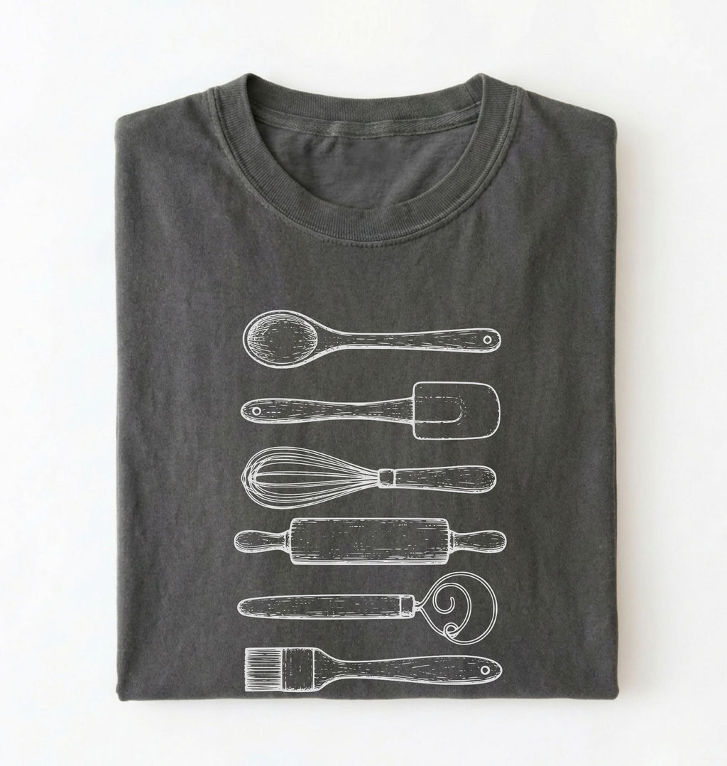 Flat ay of a Vintage baking tools shirt with whisk rolling pin and spatula illustrations on pepper tee on a white background 