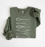 Flat lay of a military green Vintage baking tools sweatshirt featuring whisk rolling pin spatula and kitchen utensil illustrations on a white background 