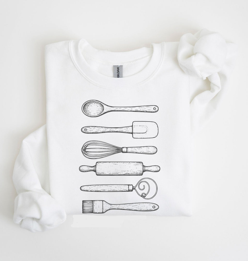 Flat lay of a white Vintage baking tools sweatshirt featuring whisk rolling pin spatula and kitchen utensil illustrations on a white background 