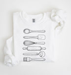 Flat lay of a white Vintage baking tools sweatshirt featuring whisk rolling pin spatula and kitchen utensil illustrations on a white background 