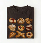 A dark brown folded t-shirt featuring a graphic print of various baked goods, including a cheesecake, croissants, a tart, and a chocolate cake, displayed against a clean white background.