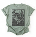 Flat lay of an light green vintage mushroom shirt green botanical fungi t shirt nature lover gift forest aesthetic design on a white background 