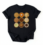 A black short-sleeve crewneck t-shirt featuring a graphic print of a 3x3 grid of various pie and tart designs on the front, displayed flat against a white background.