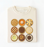 An off-white crewneck sweatshirt featuring a graphic print of nine different pies arranged in a 3x3 grid, displayed flat against a white background.