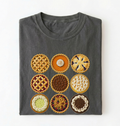 A dark gray folded t-shirt featuring a graphic print of nine different pie designs arranged in a 3x3 grid, displayed against a plain white background.