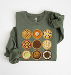 An olive green crewneck sweatshirt featuring a graphic of nine embroidered-style pies arranged in a 3x3 grid on the front. The sleeves are folded back, creating a ruffled look, and the sweatshirt is laid flat on a clean white background.