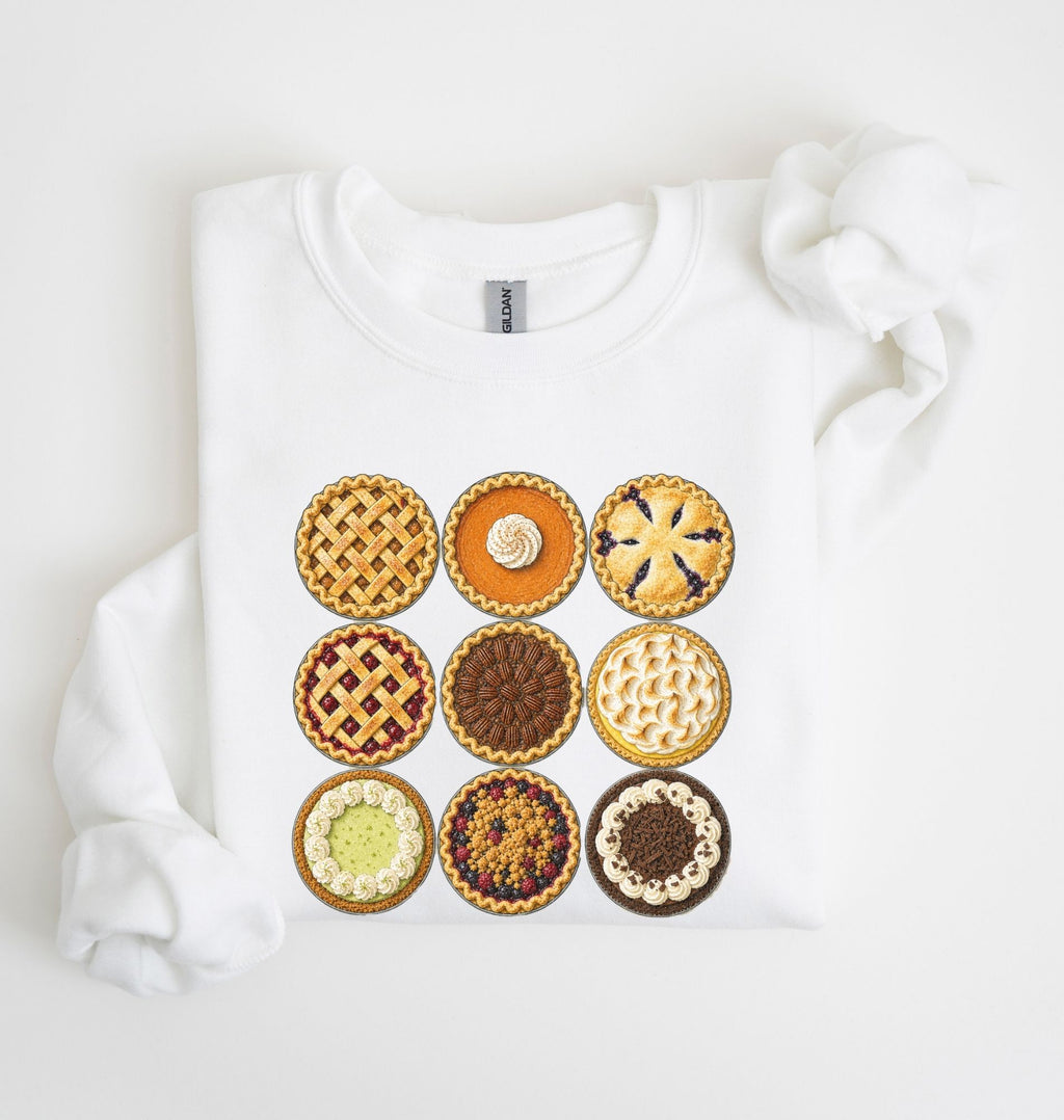 A white long-sleeve sweatshirt laid flat on a white background, featuring a graphic print of nine different decorated pies arranged in a 3x3 grid on the front.