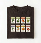 Flat lay of a brown vintage seed packet garden shirt with heirloom vegetable and herb illustrations gardener gift on a white background