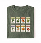 Flat lay of a green vintage seed packet garden shirt with heirloom vegetable and herb illustrations gardener gift on a white background