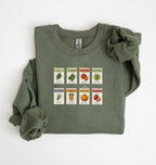 Flat lay of an green vintage seed packet garden sweatshirt with heirloom vegetable and herb illustrations gardener gift on a white background 