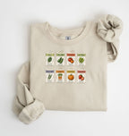 Flat lay of an sand vintage seed packet garden sweatshirt with heirloom vegetable and herb illustrations gardener gift on a white background 