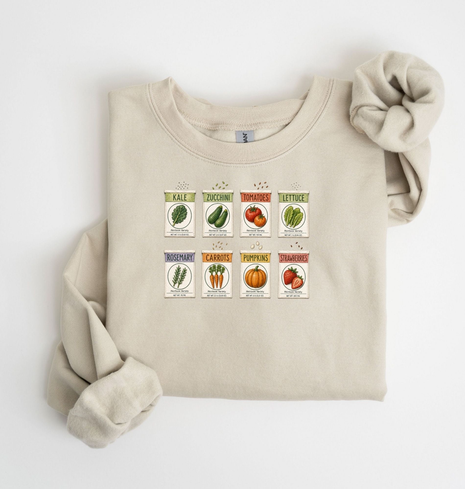 Flat lay of an sand vintage seed packet garden sweatshirt with heirloom vegetable and herb illustrations gardener gift on a white background 