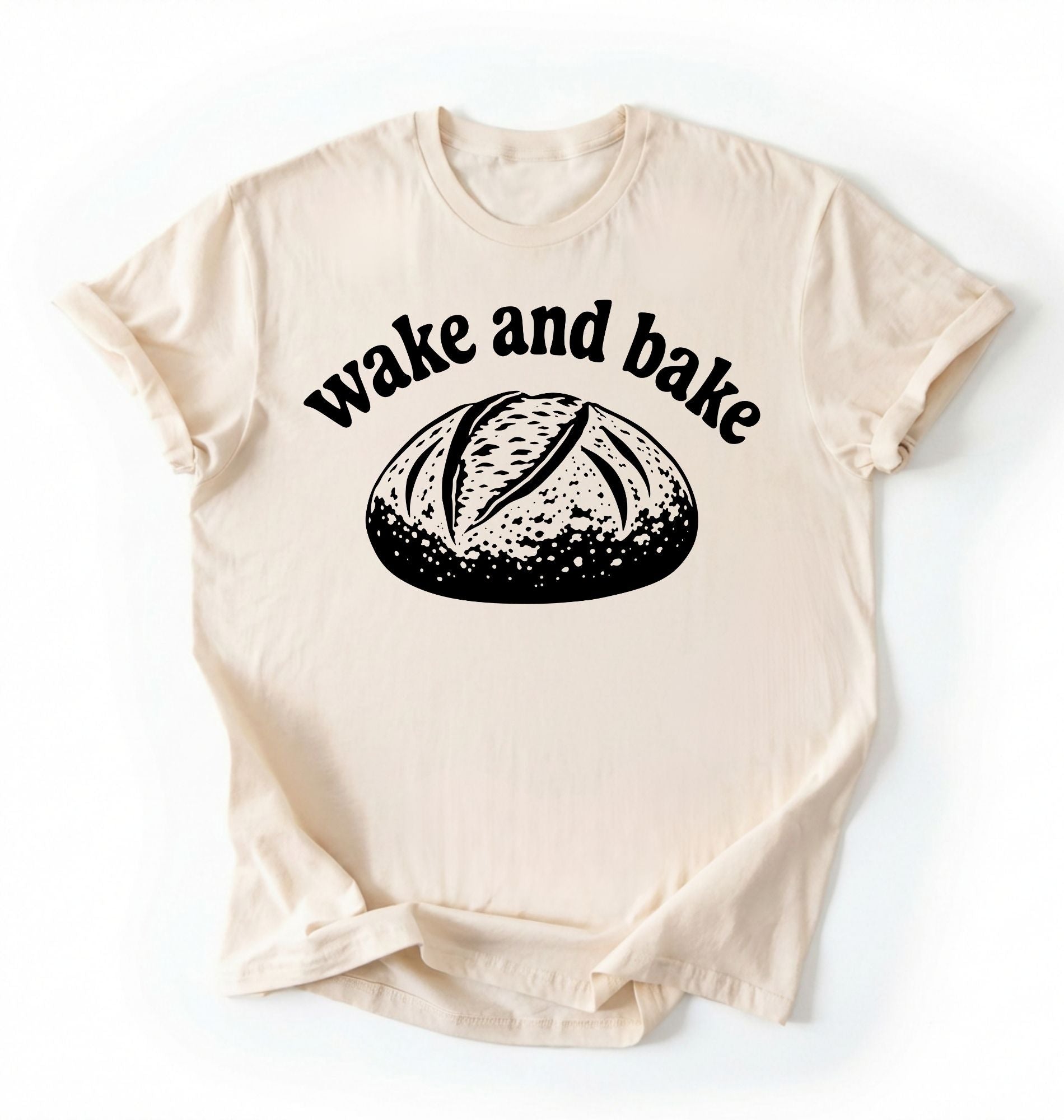 Flat lay of a Funny wake and bake bread shirt with rustic loaf illustration on cream tee on a white background