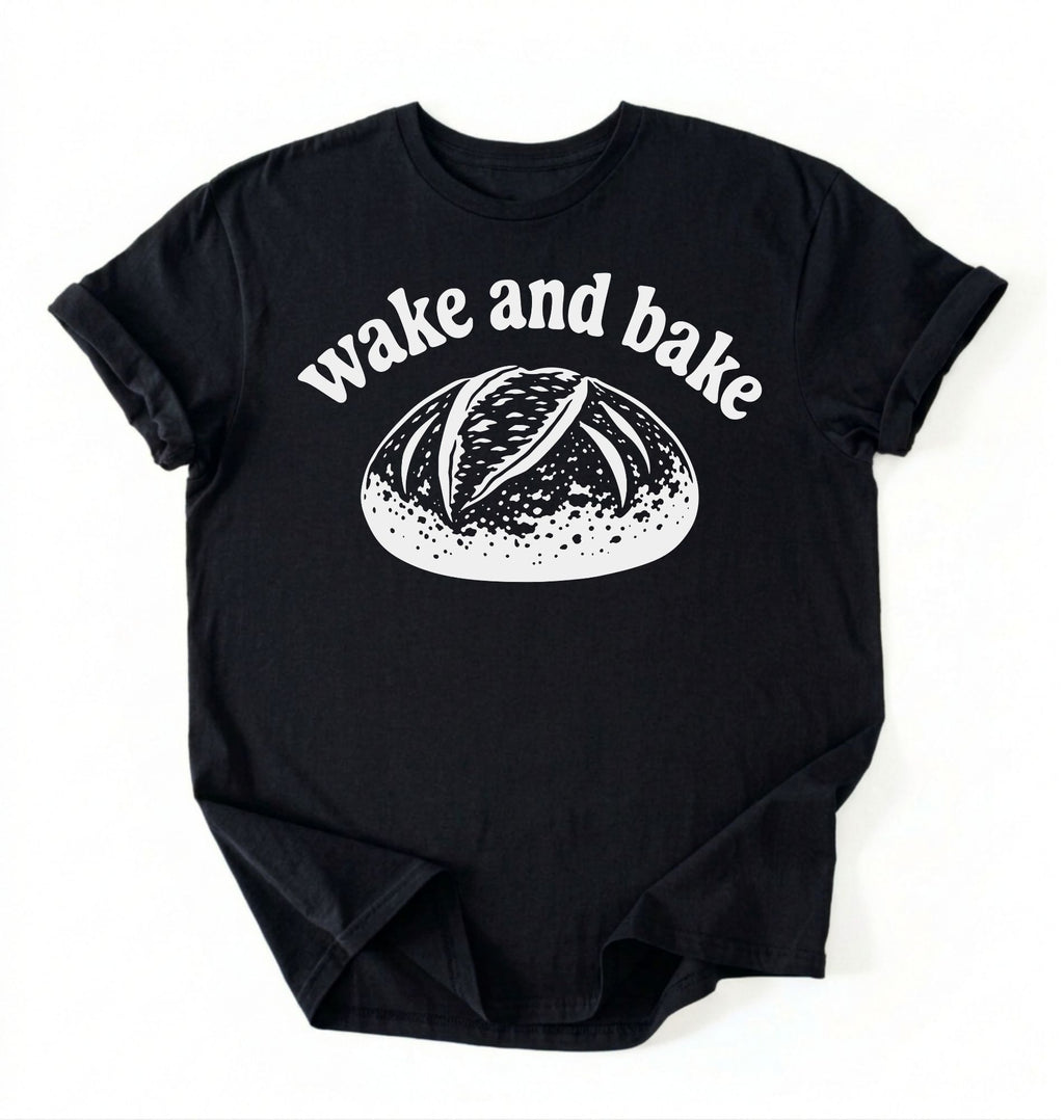 Flat lay of a Funny wake and bake bread shirt with rustic loaf illustration on black tee on a white background