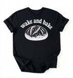 Flat lay of a Funny wake and bake bread shirt with rustic loaf illustration on black tee on a white background
