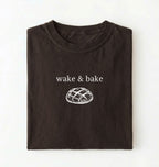 Flat lay of a dark chocolate Funny wake and bake bread shirt perfect for bakers bread lovers and home baking enthusiasts on a white background 