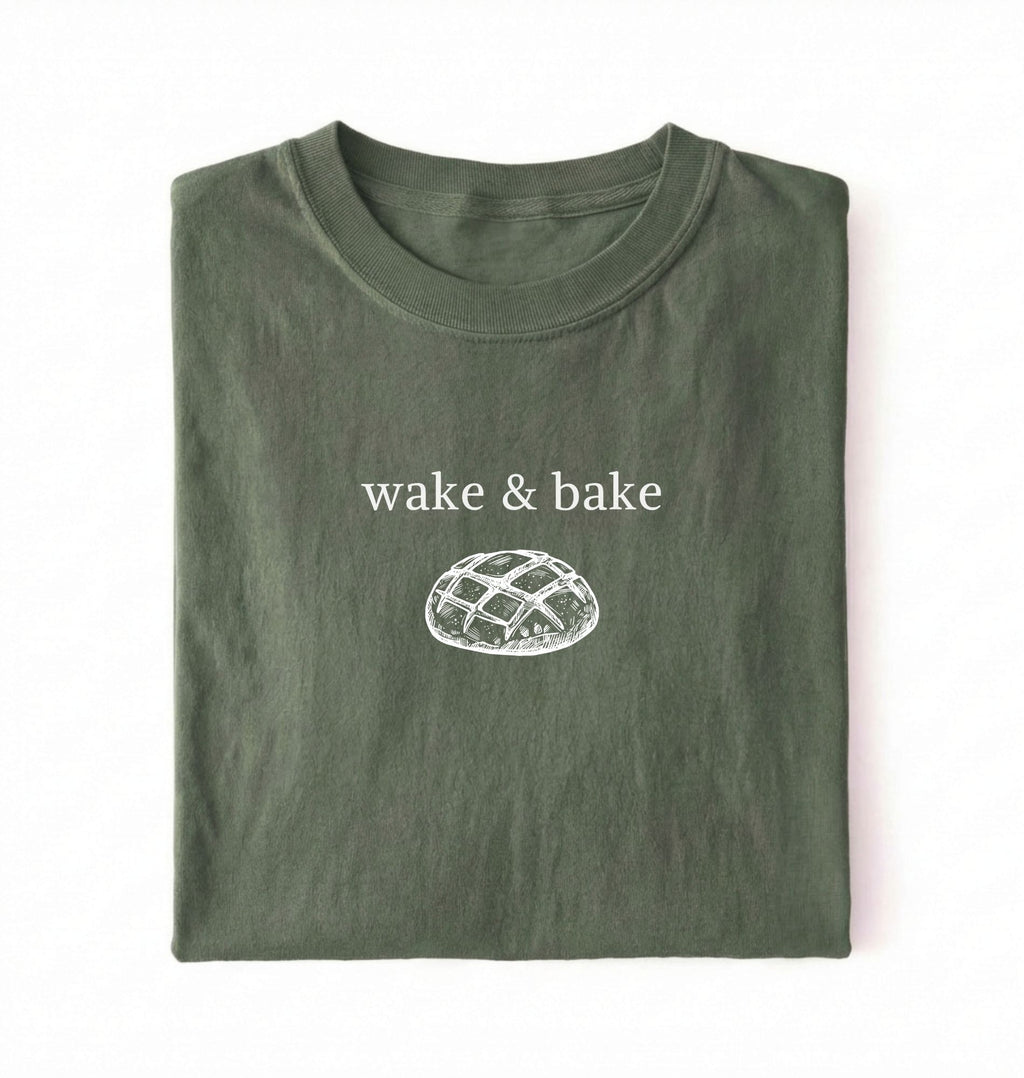 Flat lay of a moss Funny wake and bake bread shirt perfect for bakers bread lovers and home baking enthusiasts on a white background