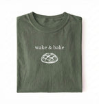 Flat lay of a moss Funny wake and bake bread shirt perfect for bakers bread lovers and home baking enthusiasts on a white background