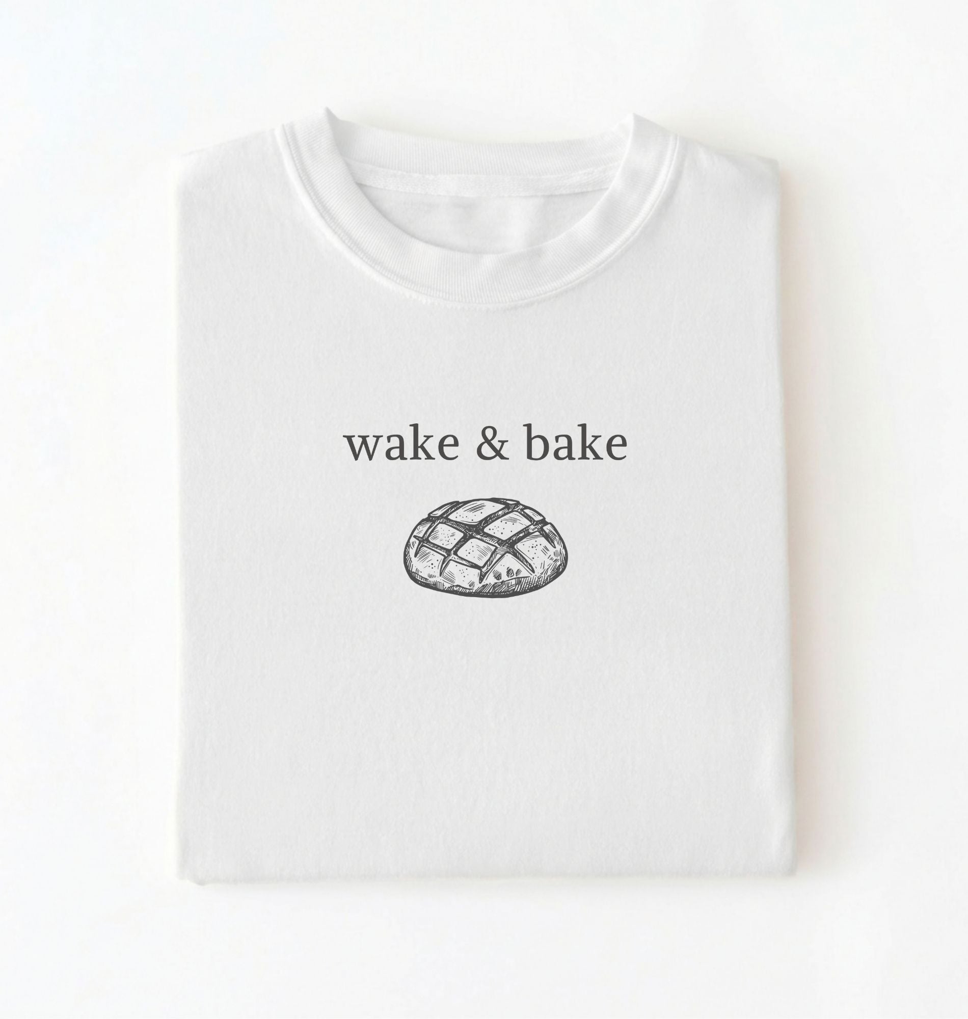 Flat lay of a white Funny wake and bake bread shirt perfect for bakers bread lovers and home baking enthusiasts on a white background