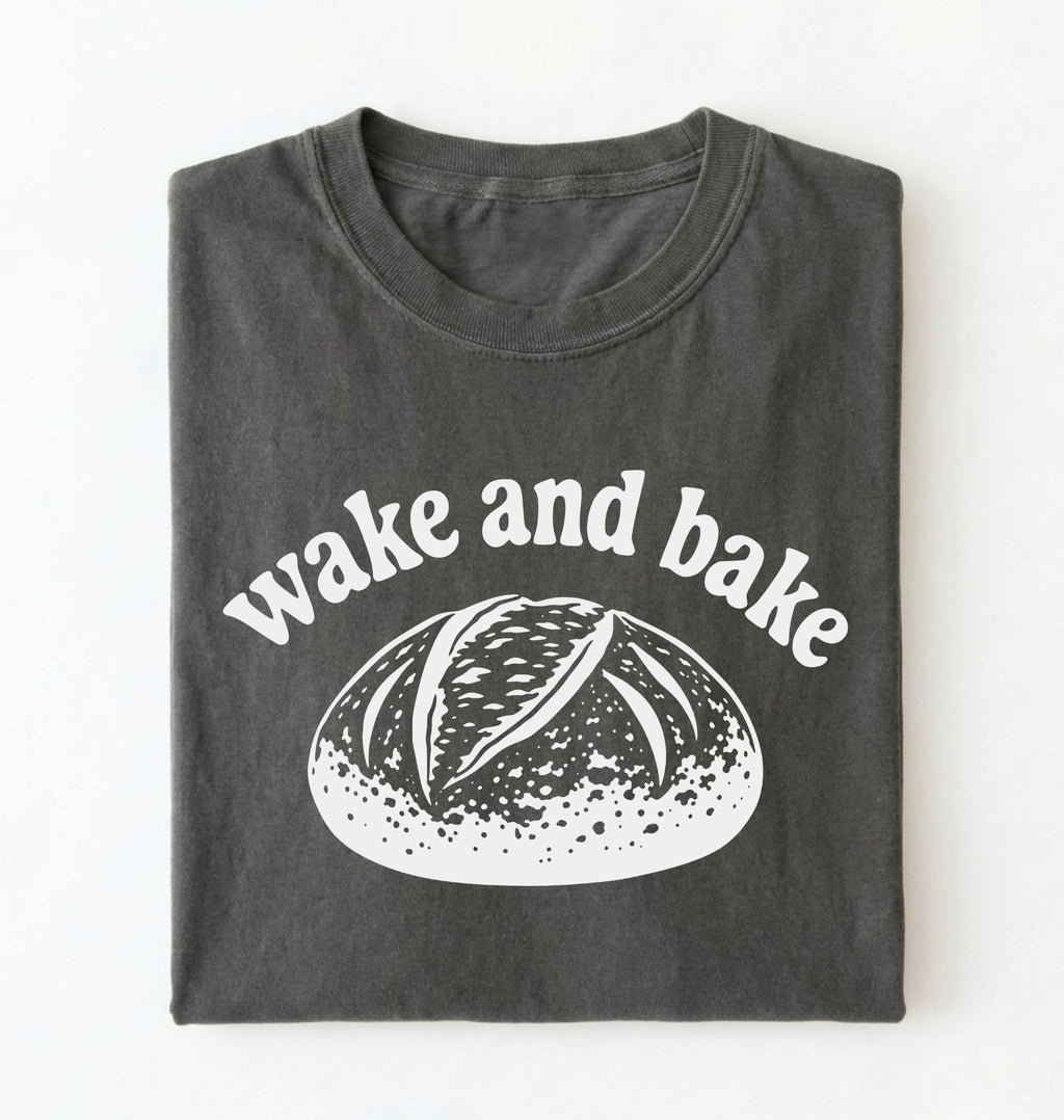Flat lay of a Funny wake and bake bread shirt with rustic loaf illustration on pepper tee on a white background