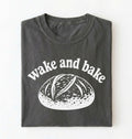 Flat lay of a Funny wake and bake bread shirt with rustic loaf illustration on pepper tee on a white background