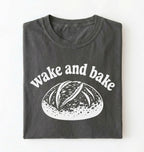 Flat lay of a Funny wake and bake bread shirt with rustic loaf illustration on pepper tee on a white background