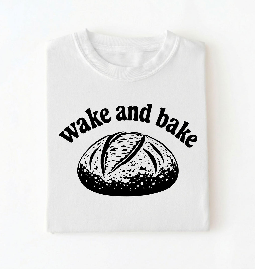 Flat lay of a Funny wake and bake bread shirt with rustic loaf illustration on white tee on a white background